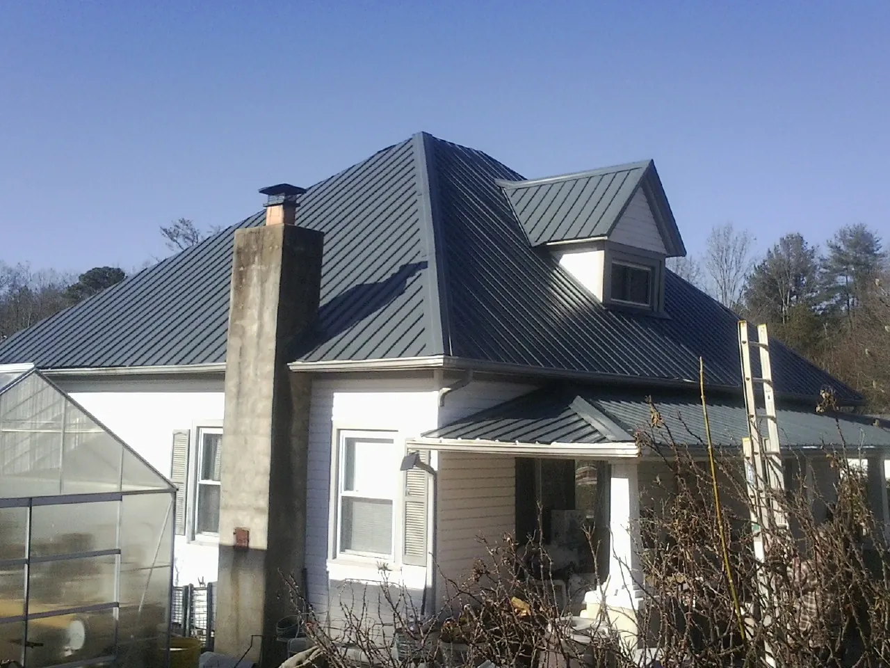 Dark blue standing seam metal roof on a white farmhouse with dormer — Slate & Tile Roof Repair by Roofing Brothers in Pittsfield