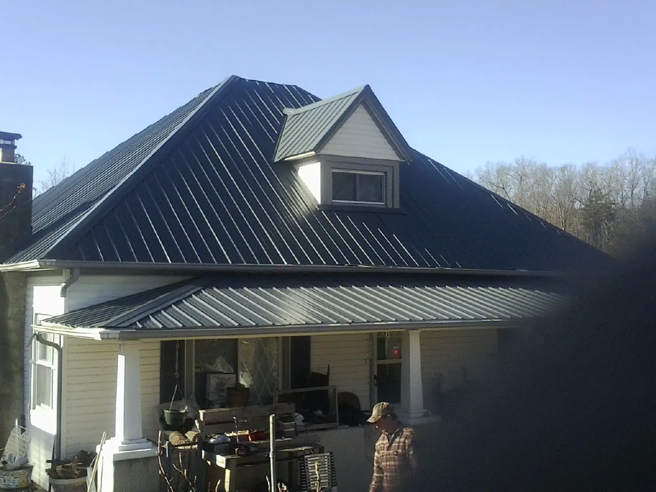 Dark blue standing seam metal roof with a dormer above a front porch in Pittsfield