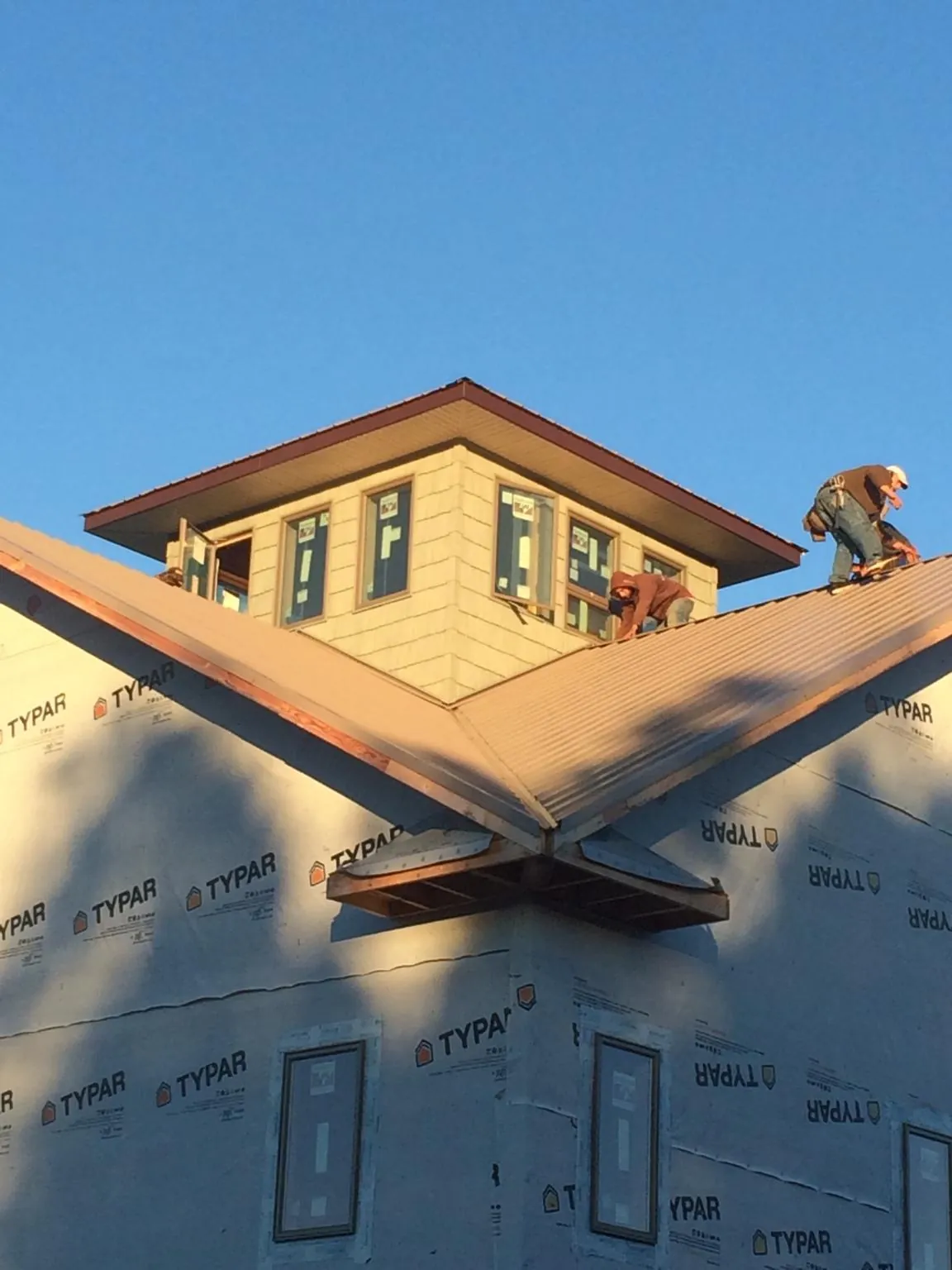 Roofers working around a rooftop cupola on a new metal roof at sunset — Roof Waterproofing in Pittsfield by Roofing Brothers